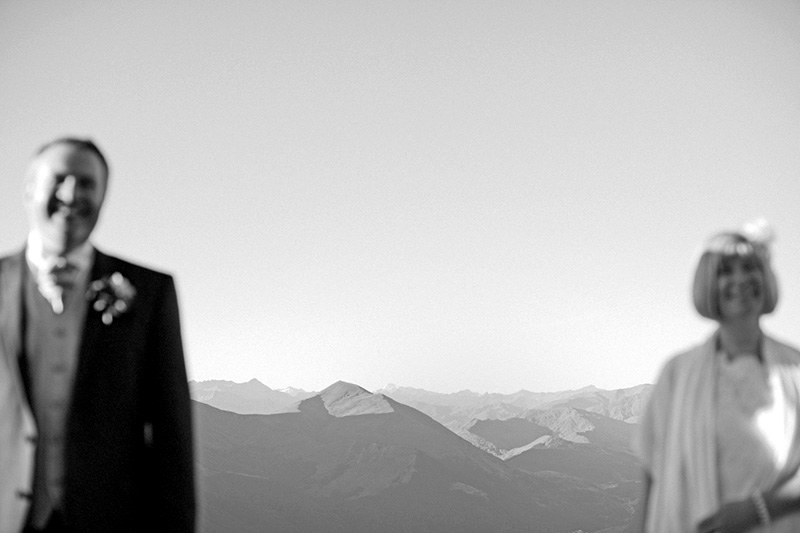 bride and groom standing apart with mountains in focus in background