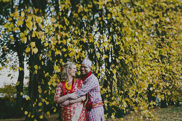 couple cuddling in front of autumn trees