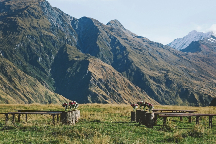 Ceremony Site, with bench seats and tree stumps with flowers in jars on them at outdoor wedding ceremony Mt Aspiring National Park, New Zealand