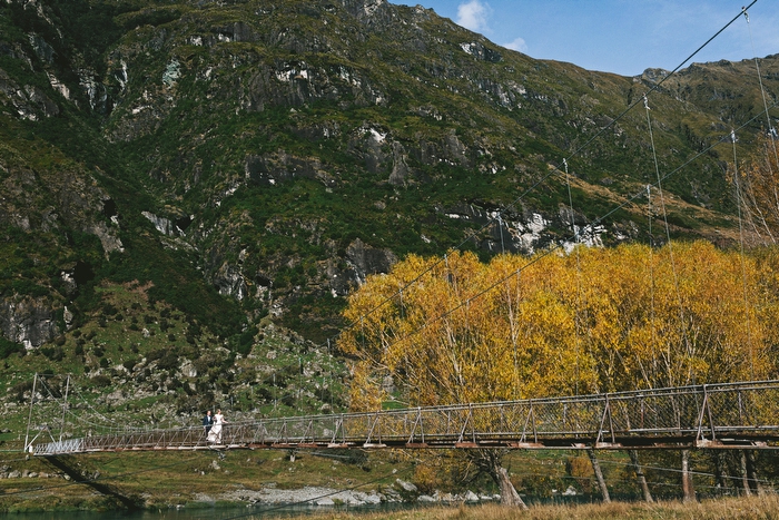 Bride arriving and walking over long swing bridge in Mt Aspiring National Park, New Zealand