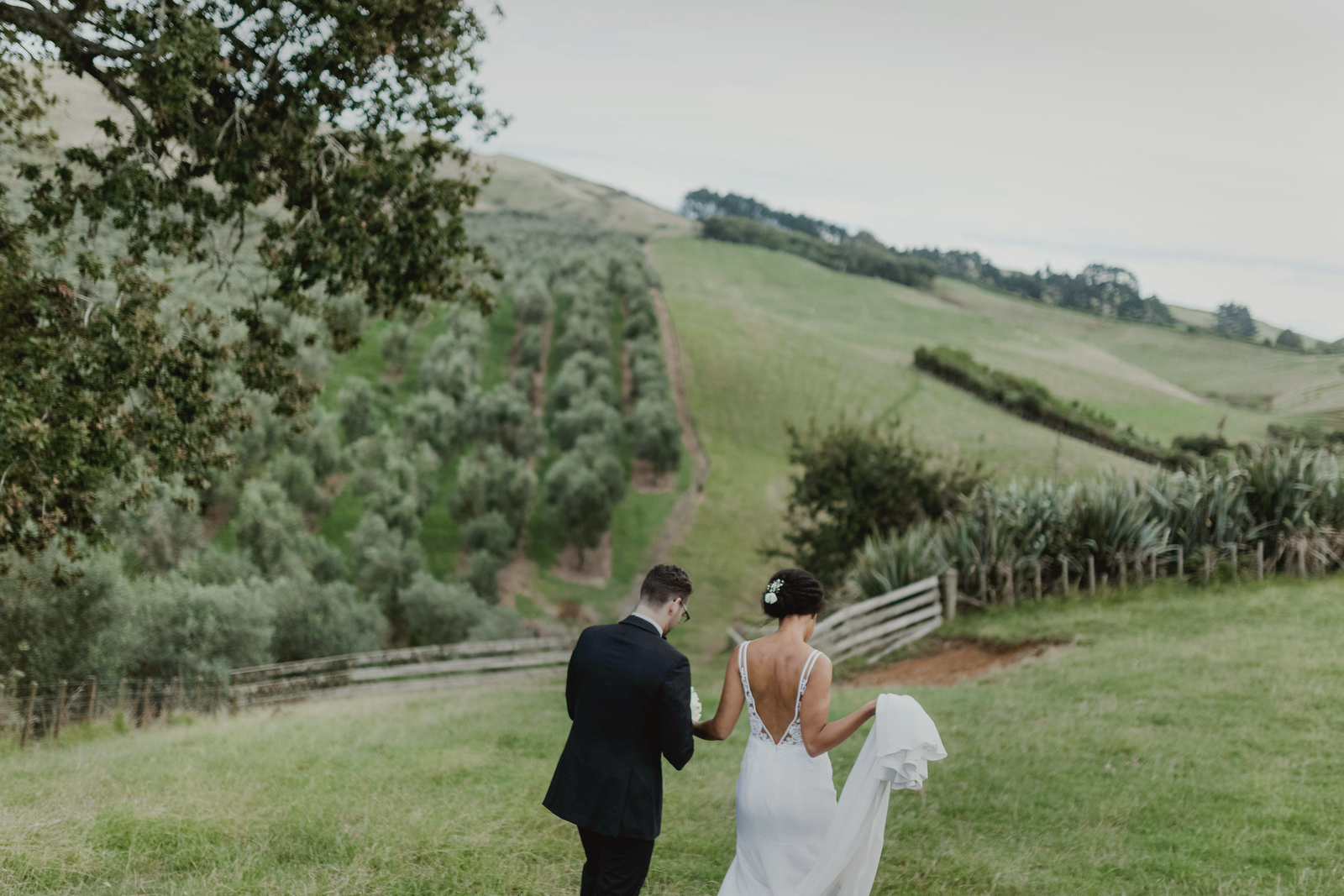 bride and groom walking towards green hills