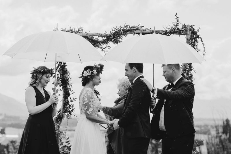 bride and groom under umbrellas b&w