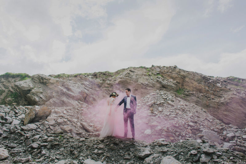 wide shot of bride and groom surrounded by pink smoke