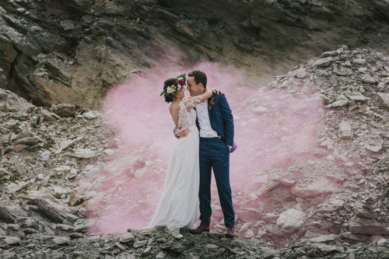 kissing bride and groom surrounded by pink smoke