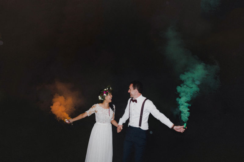 bride and groom with smoke bombs outside in the dark
