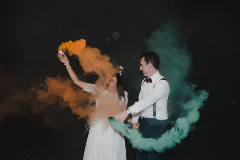bride and groom with smoke bombs outside in the dark