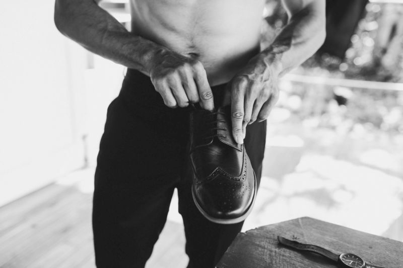 close up of groom getting dressed featuring shoe