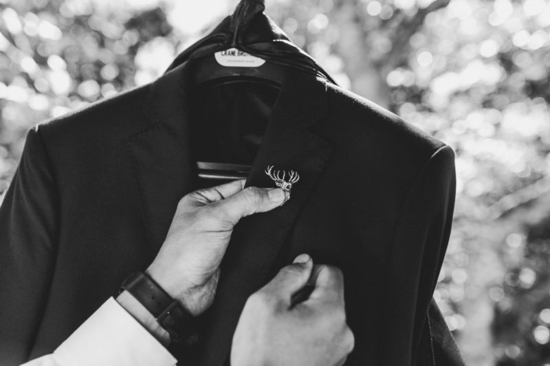 close up of groom fixing badge pin to jacket