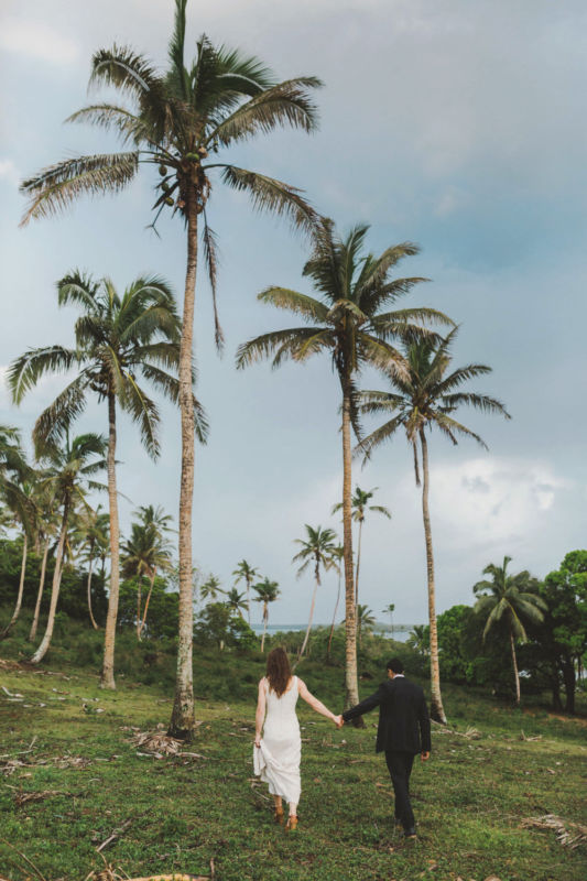 bride and groom walking into coconut plantation