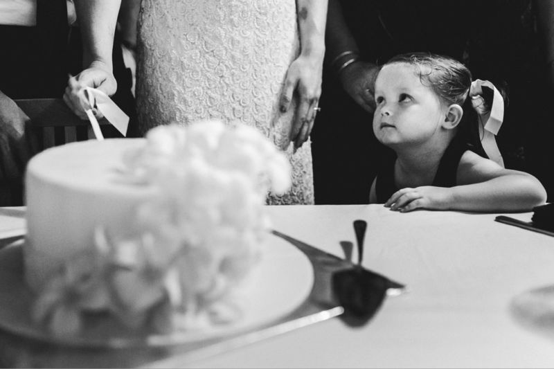 flower girl looking at bride and cake cutting