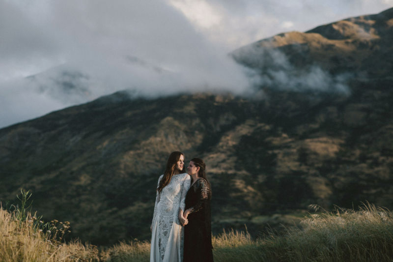 brides embracing with dramatic mountain behind them - spooning each other