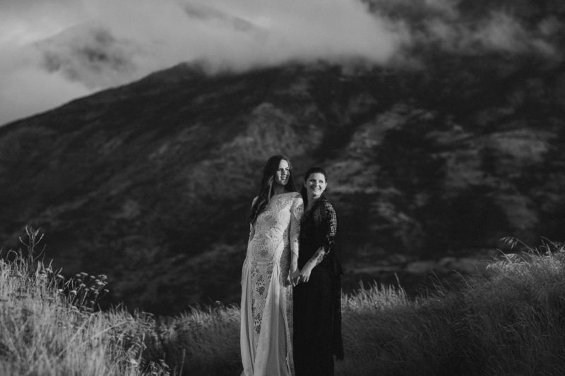 brides embracing with dramatic mountain behind them - spooning each other b&w
