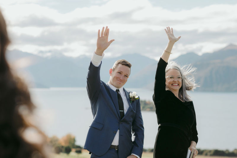 groom and pastor waving to bride