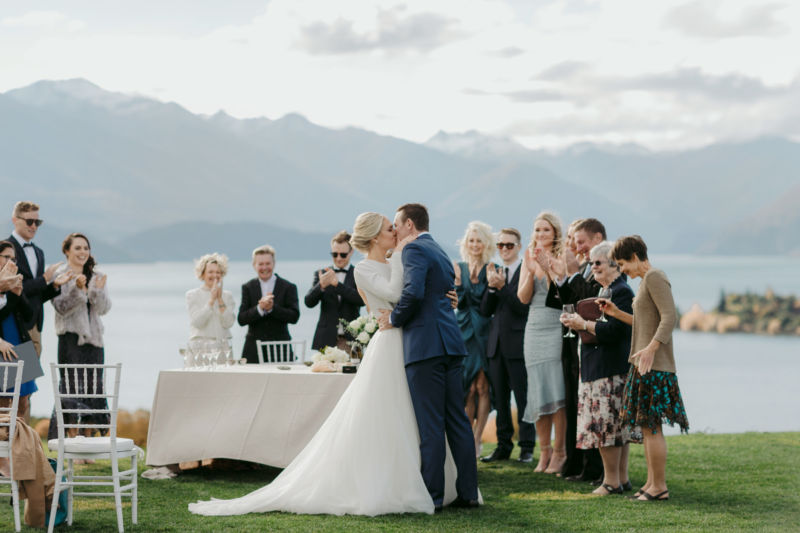 first kiss with guests and mountains and lakes in the background