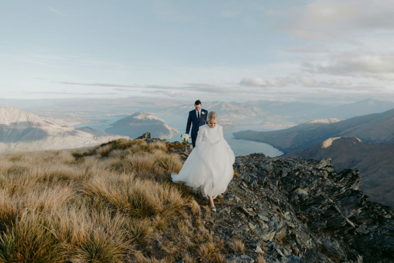 bride and groom on mountaintop walking towards camera