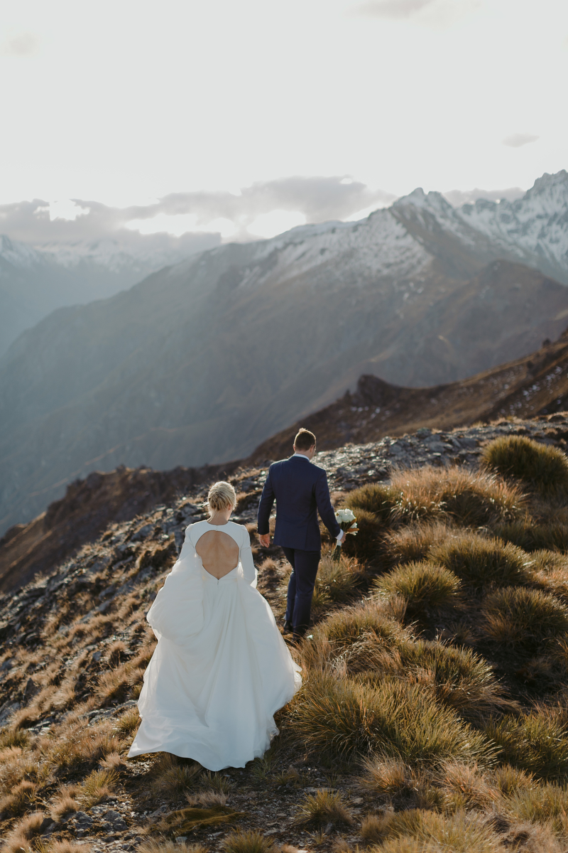 bride and groom on mountaintop walking away from camera