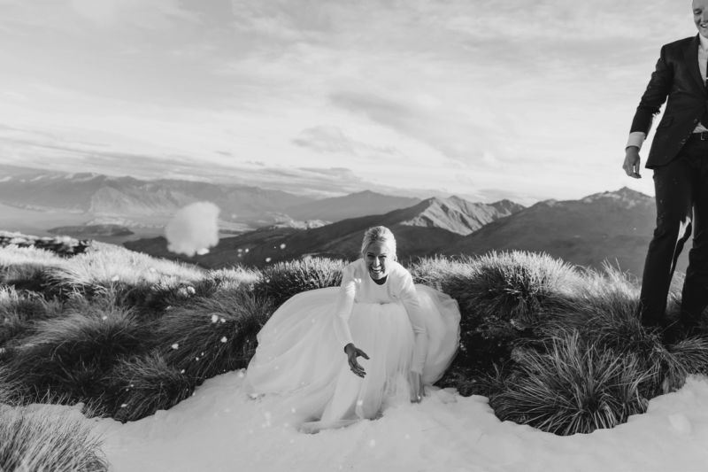 bride and groom on mountaintop bride aiming a snowball at camera