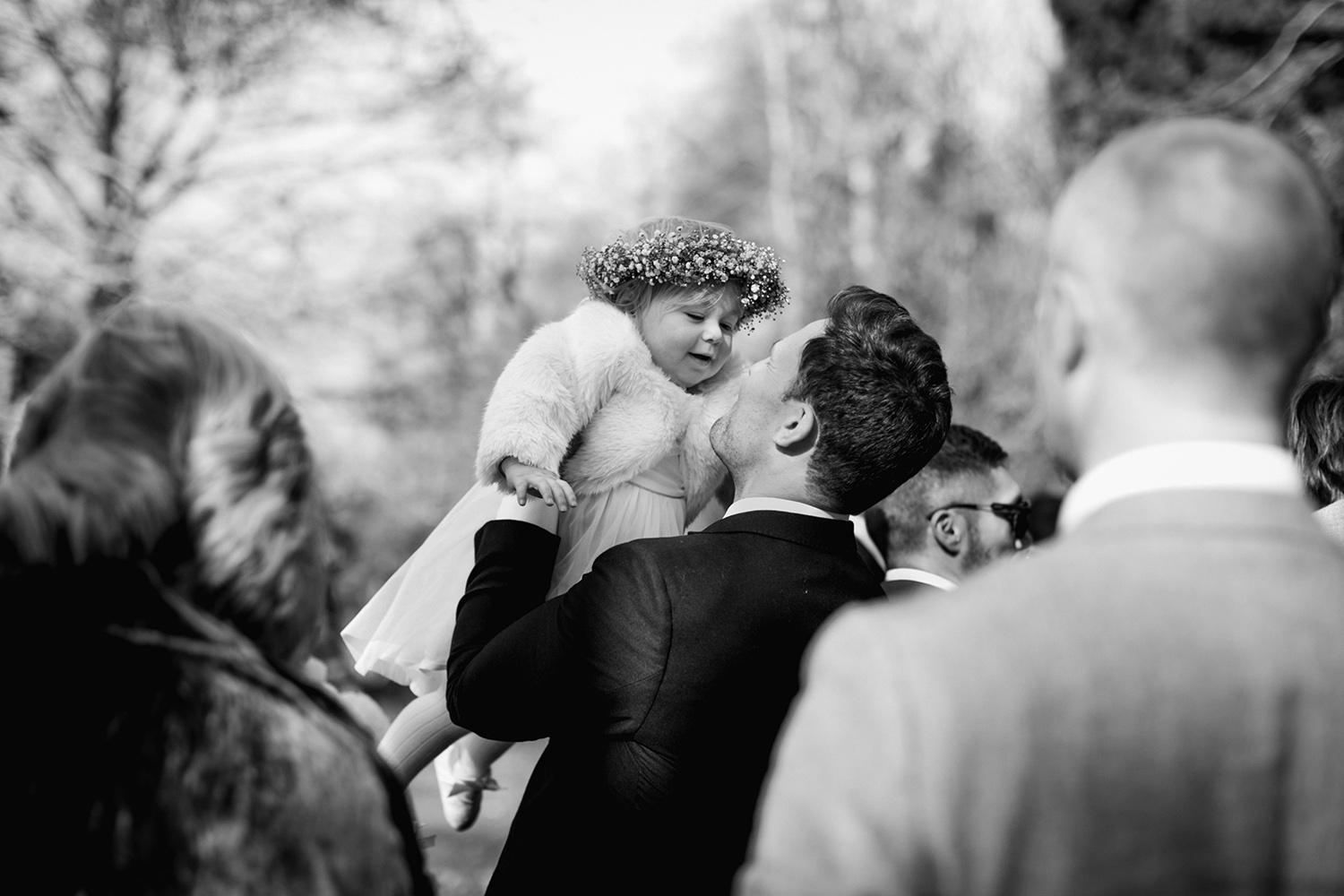 flower girl with flower crown being lifted into the air by groom