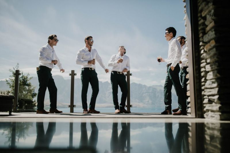 groomsmen drinking with mountain background and reflection on ground