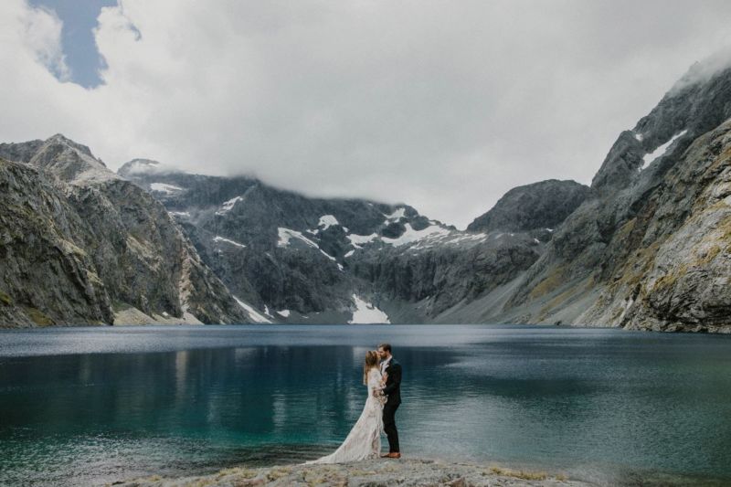 bride and groom kissing in front of lake wide angle