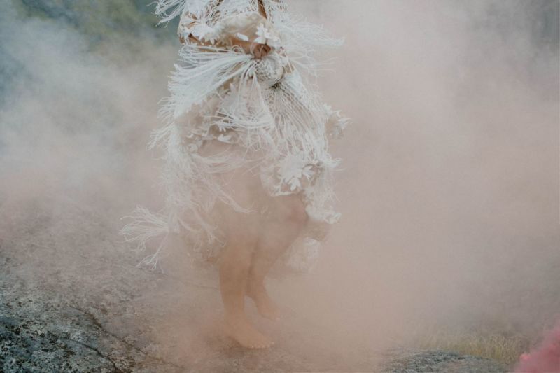 close up of bride swishing dress in cloud of smoke