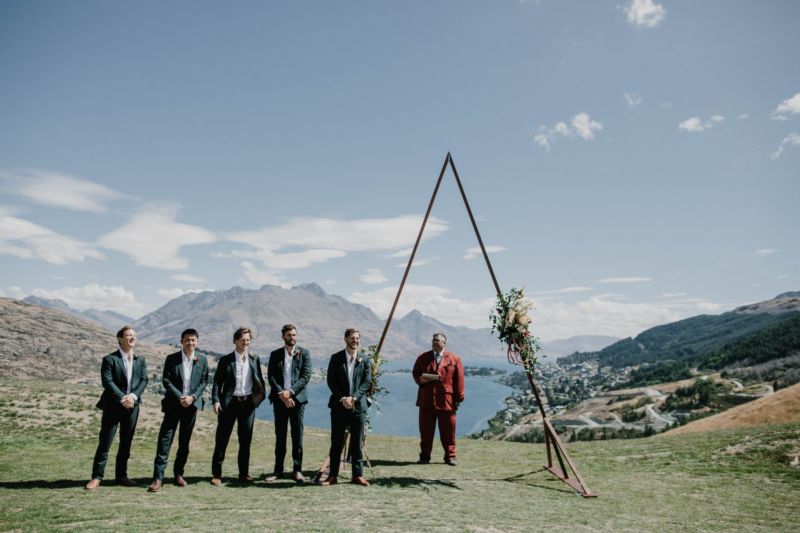 groom, groomsmen and celebrant waiting at the ceremony site with arch