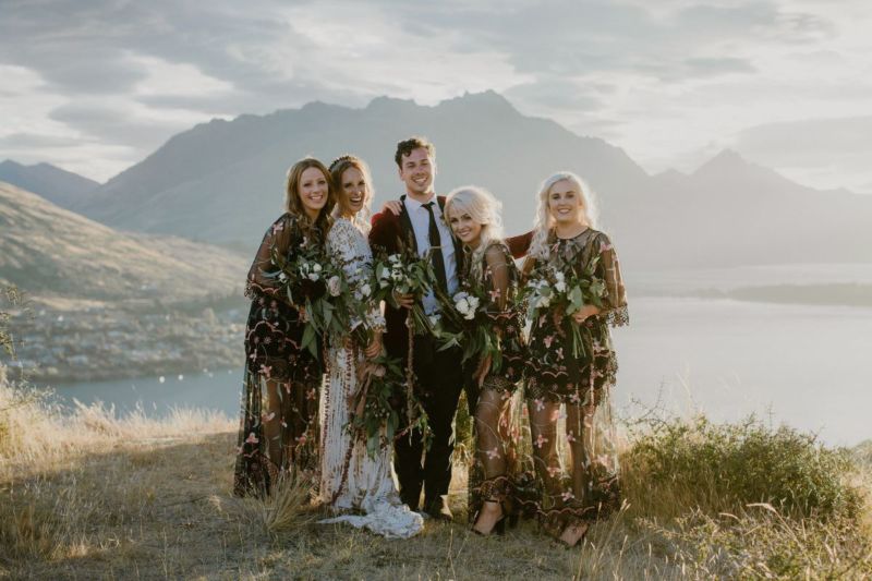 Bride, bridesmaid and bridesman pose for a portrait in sunset light in front of mountains and lake
