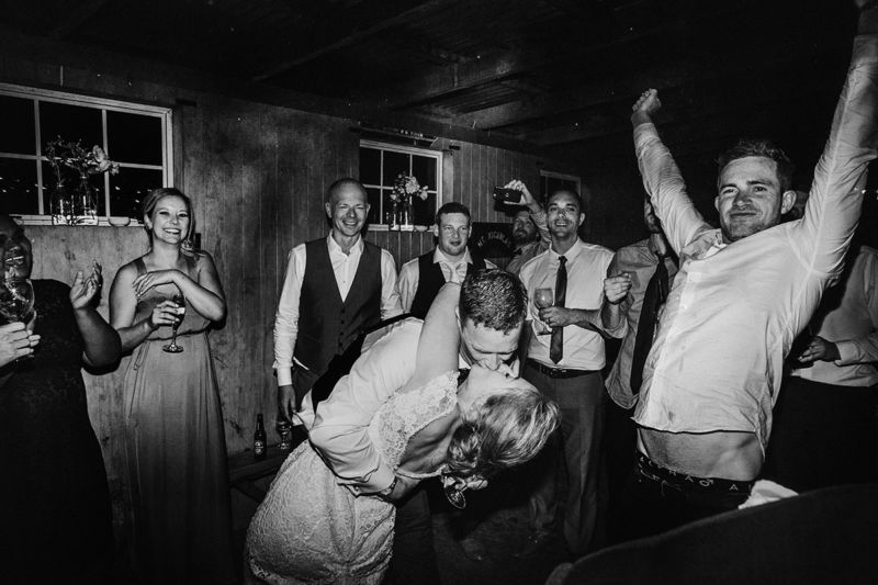 messy dance floor bride and groom kissing and guests celebrating
