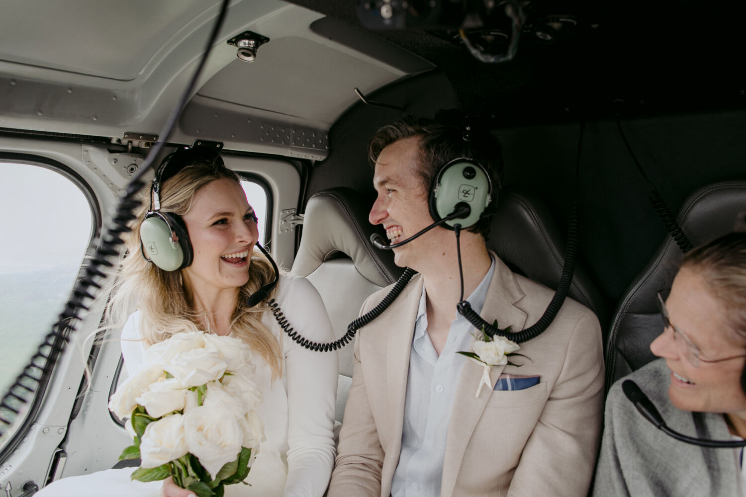 Bride and groom laugh with celebrant in the helicopter