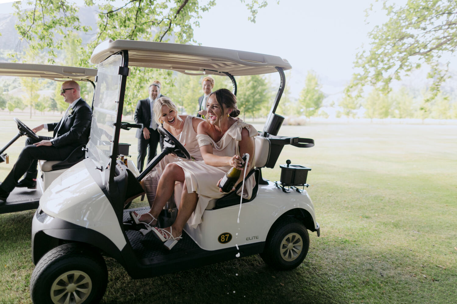 Bridesmaids popping bubbles on golf cart at Millbrook Summer Wedding Queenstown