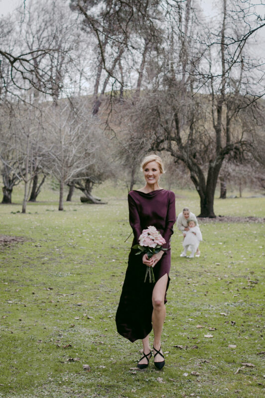 Bridesmaid beginning ceremony walking with flowers in a beautiful wine coloured dress