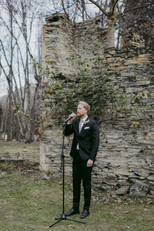 Groomsmen singing into a microphone to begin ceremony