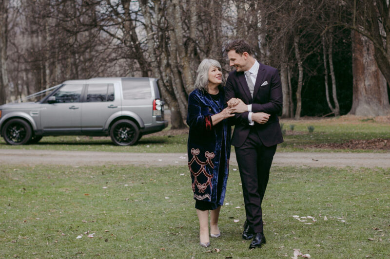 Groom and his mum sharing a smile while walking up the aisle
