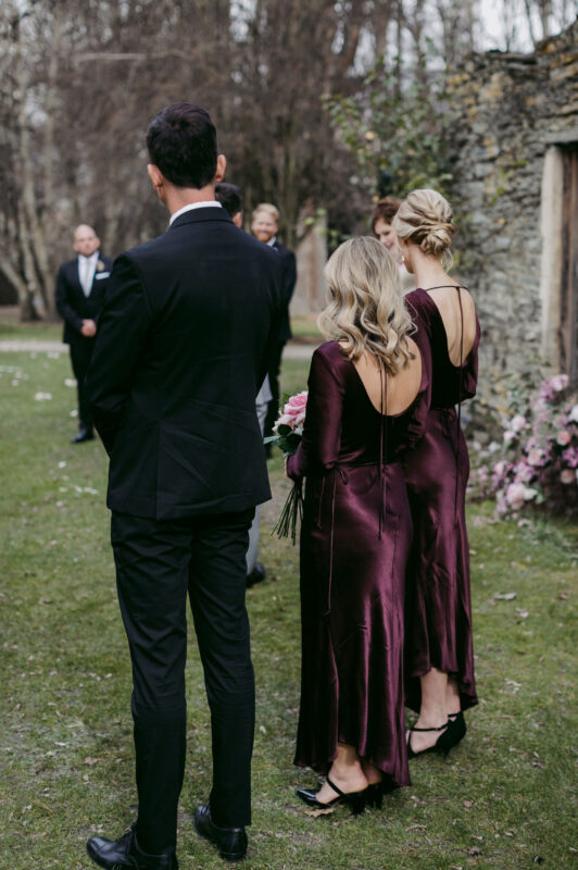 Bridesmaids and bridesman from behind during ceremony showing dress details