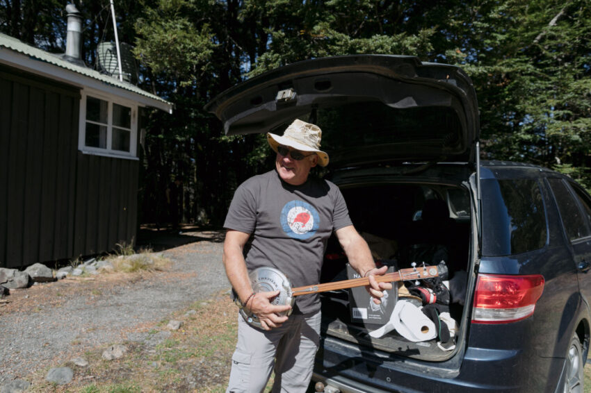 Man with floppy hat getting banjo out of car boot