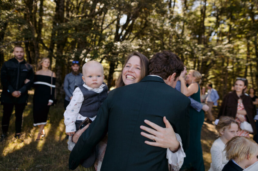 Woman holding child hugging the groom