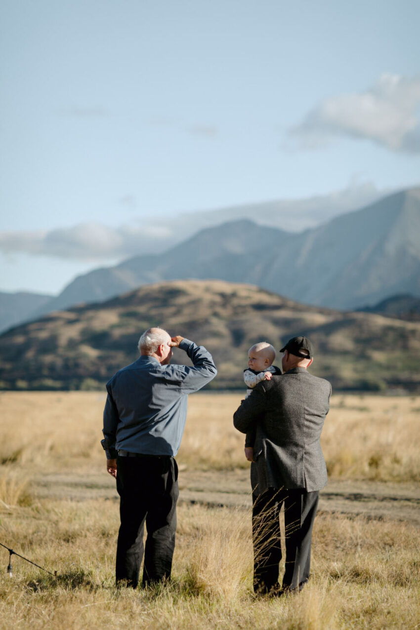 Men holding toddler looking at view