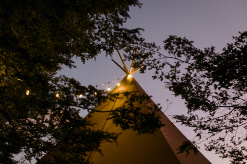 Sunset colours and tipi through beech trees