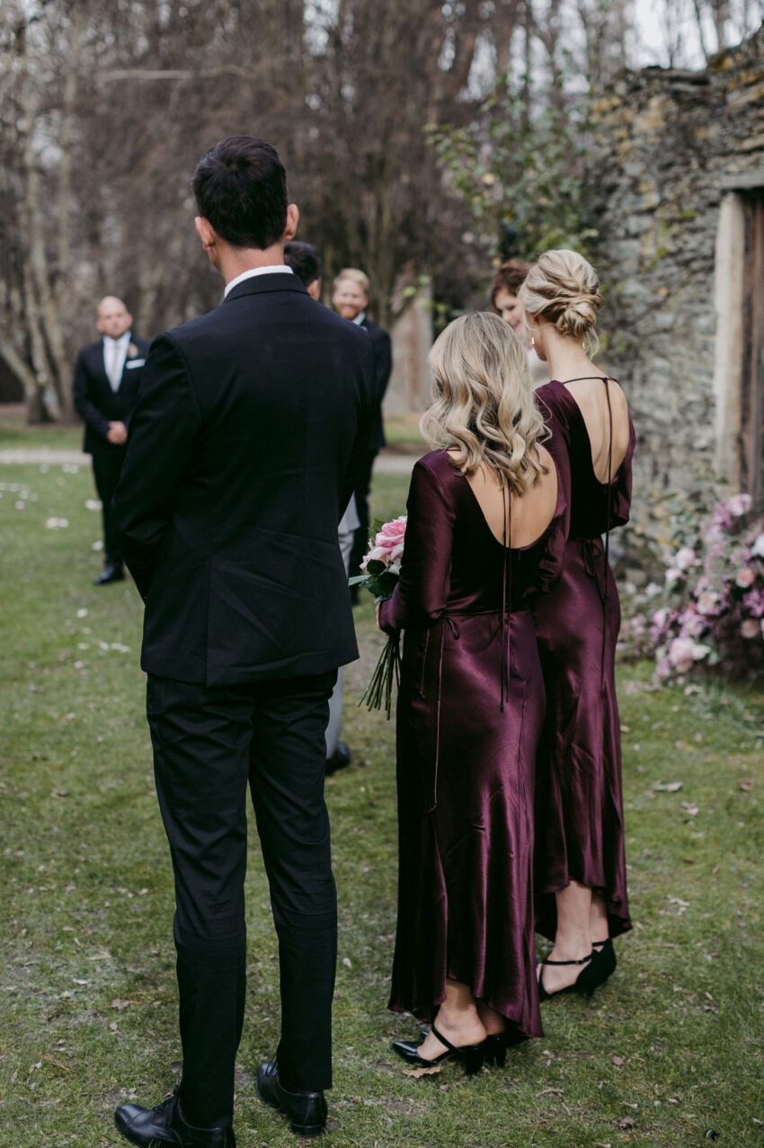 Bridesmaids and bridesman from behind during ceremony showing dress details