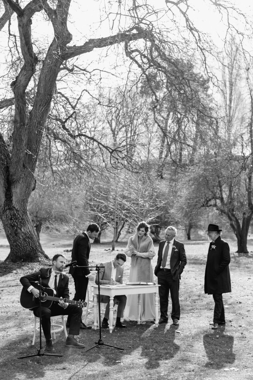 The group gathers under trees for the signing of the register