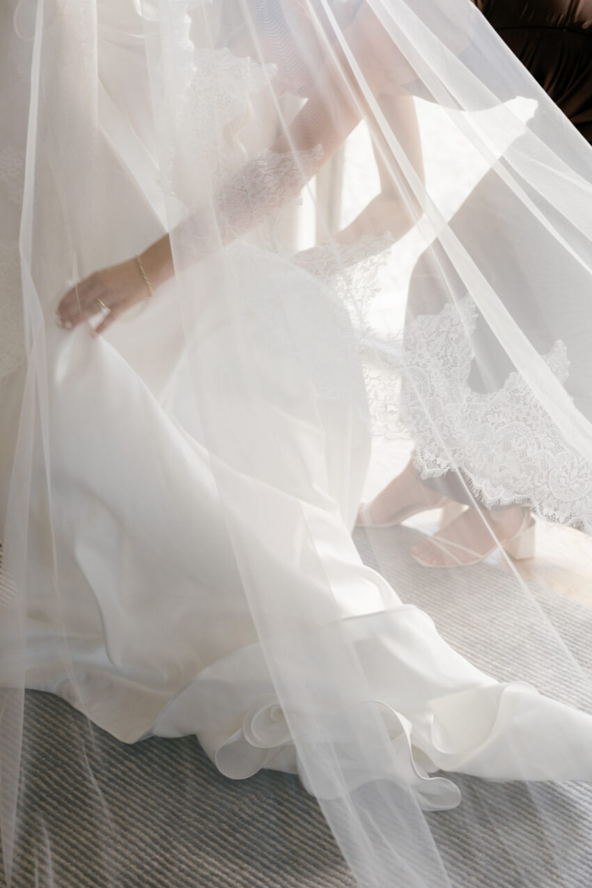 a glimpse of a bridesmaid under the veil as she fixes the brides dress