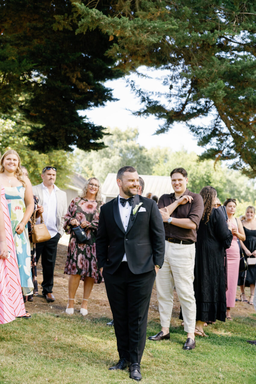 the groom in amongst a crowd of guests awaiting the brides arrival