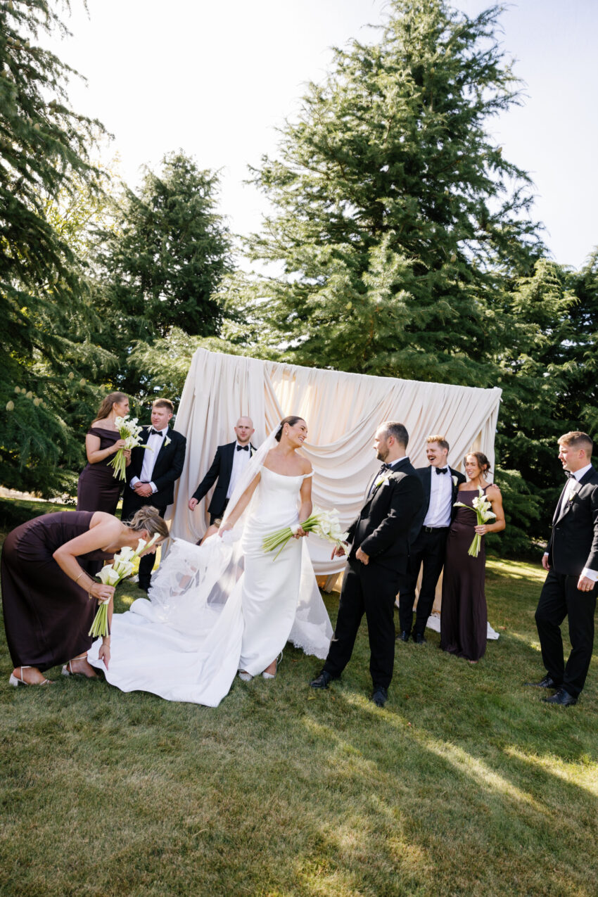 The whole bridal party in front of a draped backdrop in a candid moment