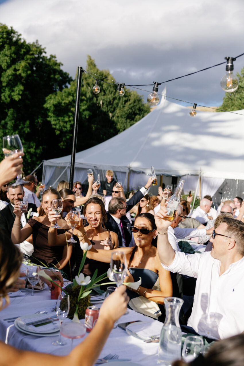 Reception scene with guests cheering and the tent in the background