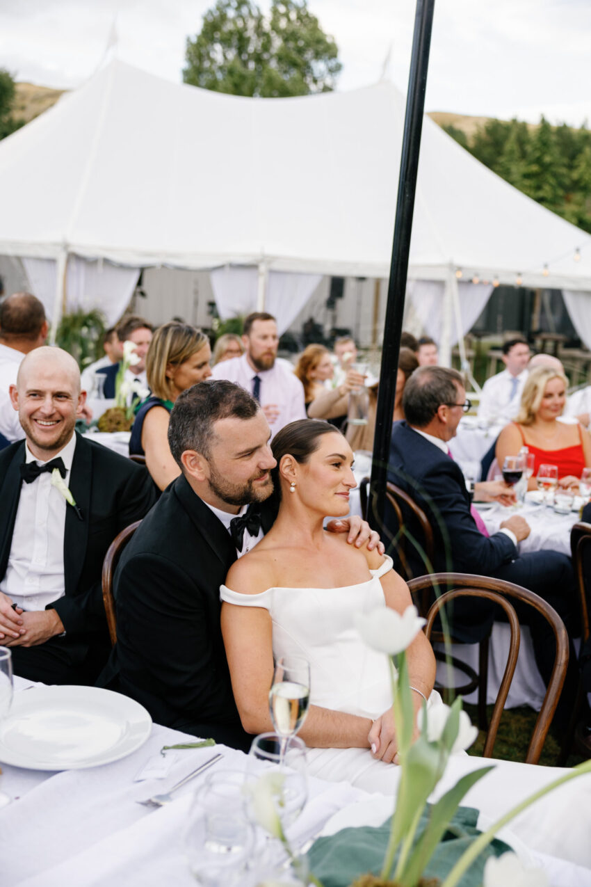 Bride and groom cuddle up and listen to speeches