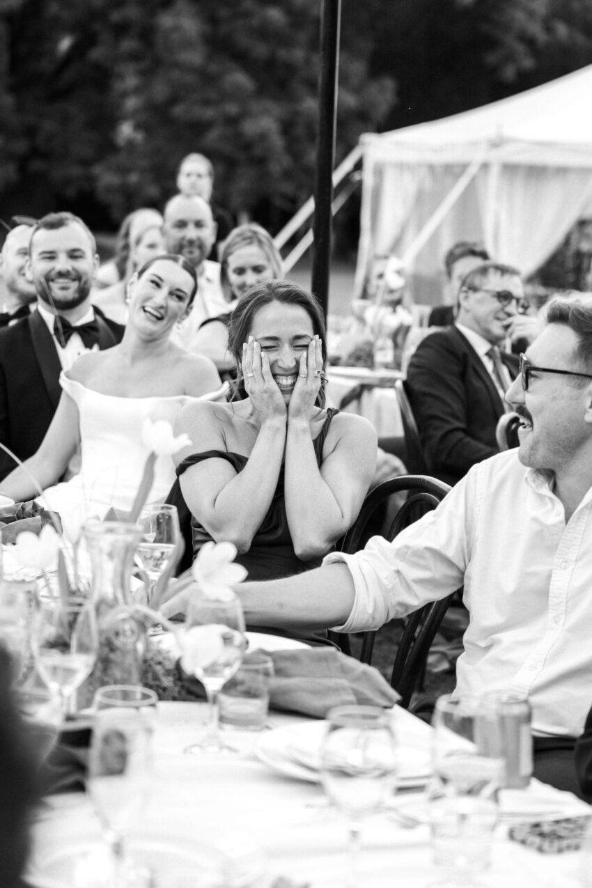 Bridesmaid holds her face in a fun laugh during speeches