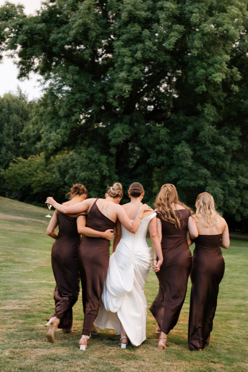 Bride and her 4 bridesmaids walking away sharing a cuddle and a moment colour