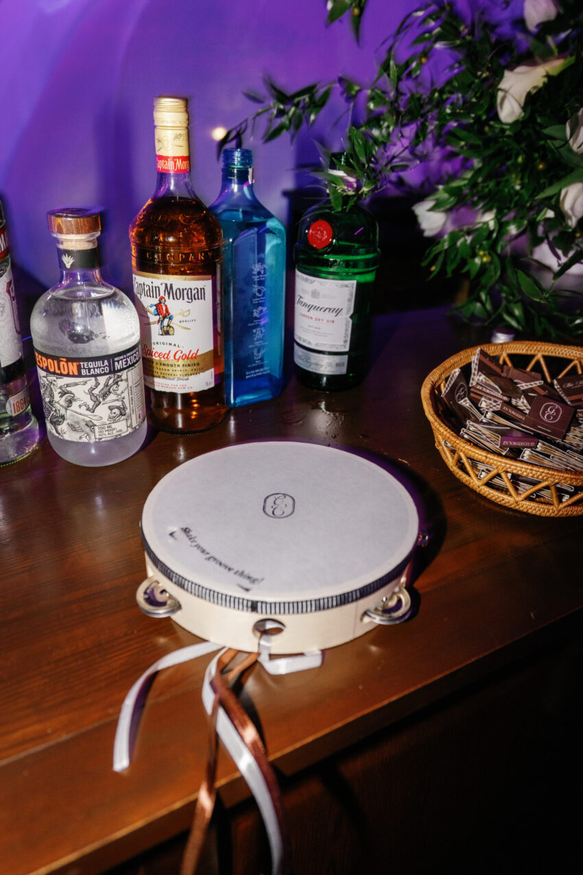 Close up of monogrammed tamborine at the bar with bottles in the background