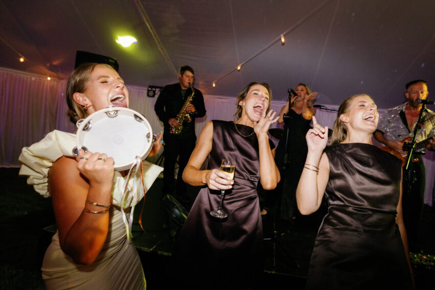 Bridesmaids and guests having fun on the dancefloor with tamborines