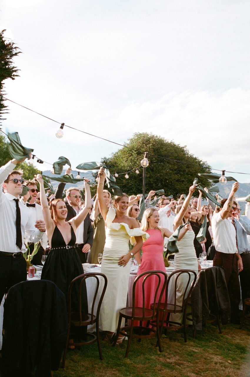 Colour shot of guests cheering and holding napkins in the air in excitement